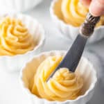 Butter knife cutting into a swirl of whipped honey butter in a ramekin.