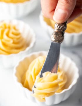 Butter knife cutting into a swirl of whipped honey butter in a ramekin.