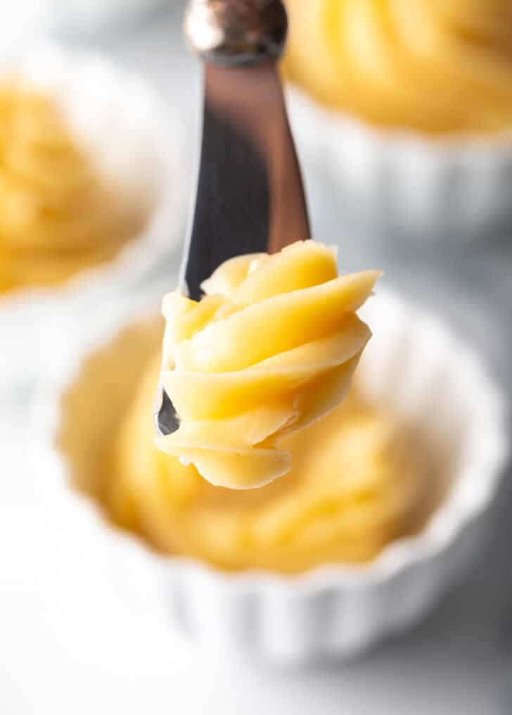 Butter knife cutting into a swirl of whipped honey butter in a ramekin.