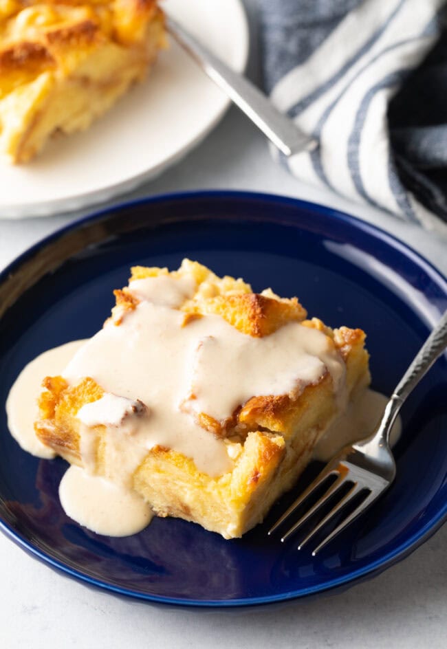 Slice of bread pudding with vanilla sauce poured on top.