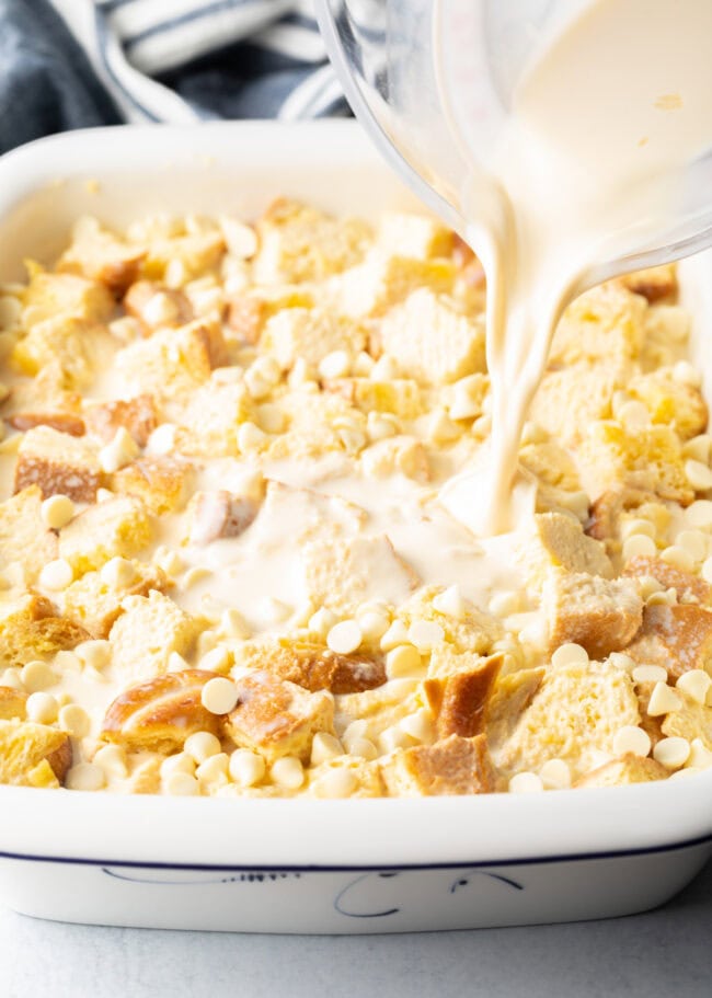 Bread pudding mixture being poured over chunks of brioche.